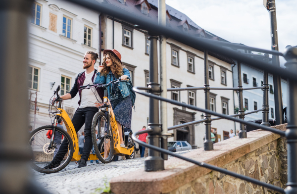 Young tourist couple travellers with electric scooters in small town, sightseeing.