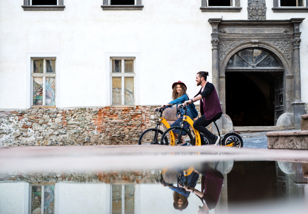 Young tourist couple travellers riding electric scooters in small town, sightseeing. Copy space.