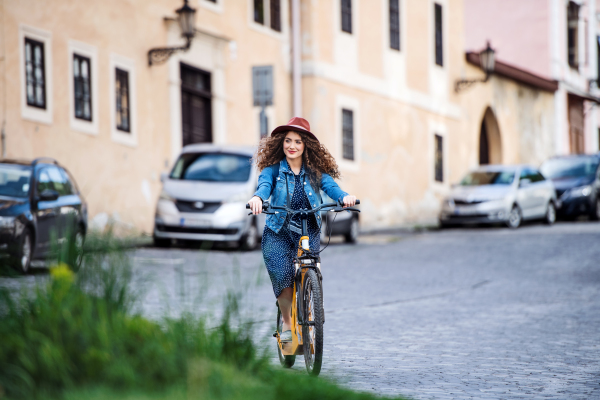 Beautiful young woman tourist traveller with electric scooter in small town, sightseeing.