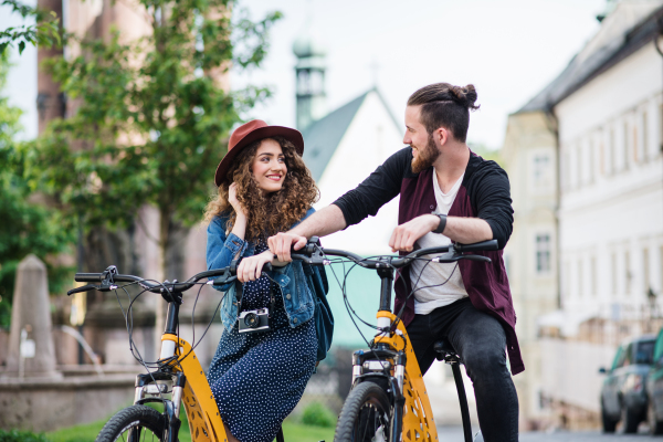 Young tourist couple travellers with electric scooters in small town, sightseeing.