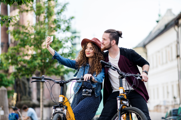 Young tourist couple travellers with electric scooters and smartphone in town, taking selfie.