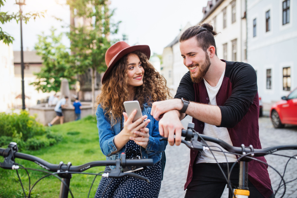 Young tourist couple travellers with smartphone and electric scooters in small town, sightseeing.