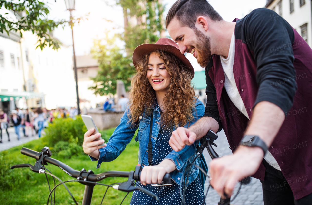 Young tourist couple travellers with electric scooters and smartphone in town, taking selfie.