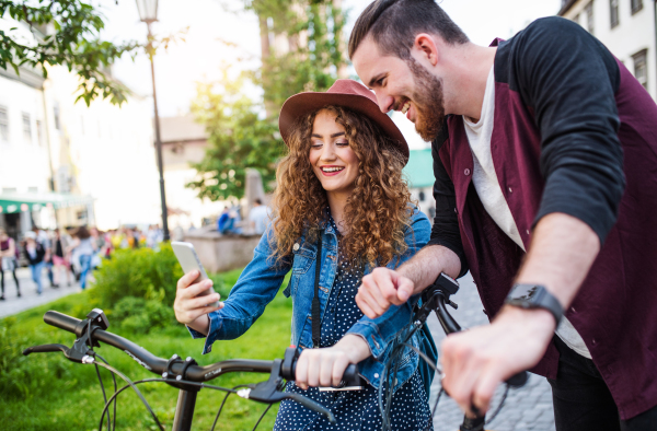 Young tourist couple travellers with electric scooters and smartphone in town, taking selfie.