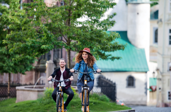 Young tourist couple travellers with electric scooters in small town, sightseeing.