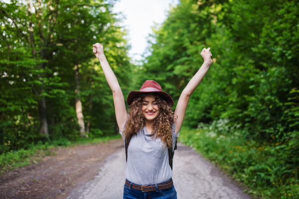 Front view of young tourist woman traveller walking in nature, stretching arms.