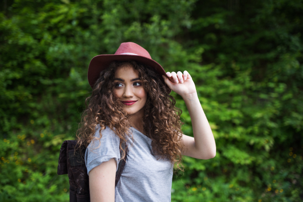 Front view of young tourist woman traveller with backpack walking in nature.