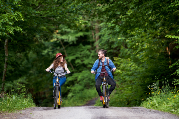 Young tourist couple travellers with backpacks and electric scooters in nature.