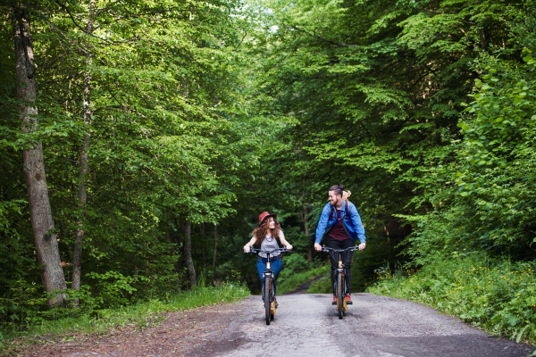 Young tourist couple travellers with backpacks and electric scooters in nature.