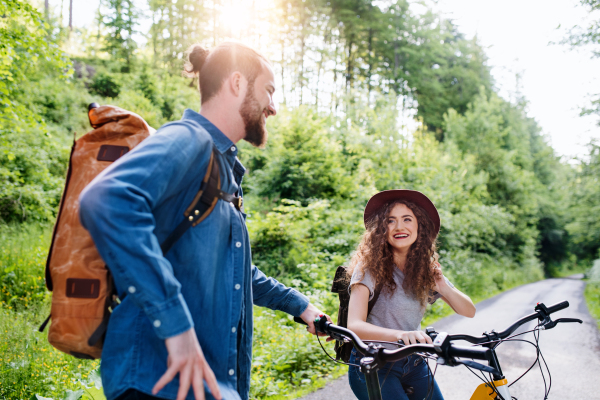 Young tourist couple travellers with backpacks and electric scooters in nature, resting.