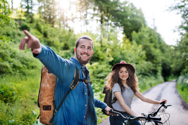 Young tourist couple travellers with backpacks and electric scooters in nature, resting.