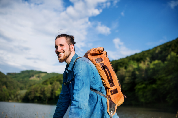 Young happy tourist man traveller with backpack standing in nature, resting.