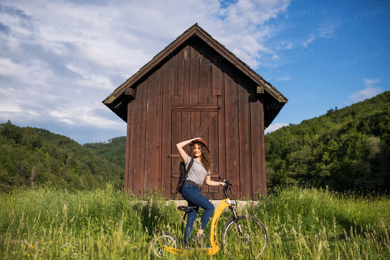 Young tourist woman traveller with electric scooter in nature, resting.