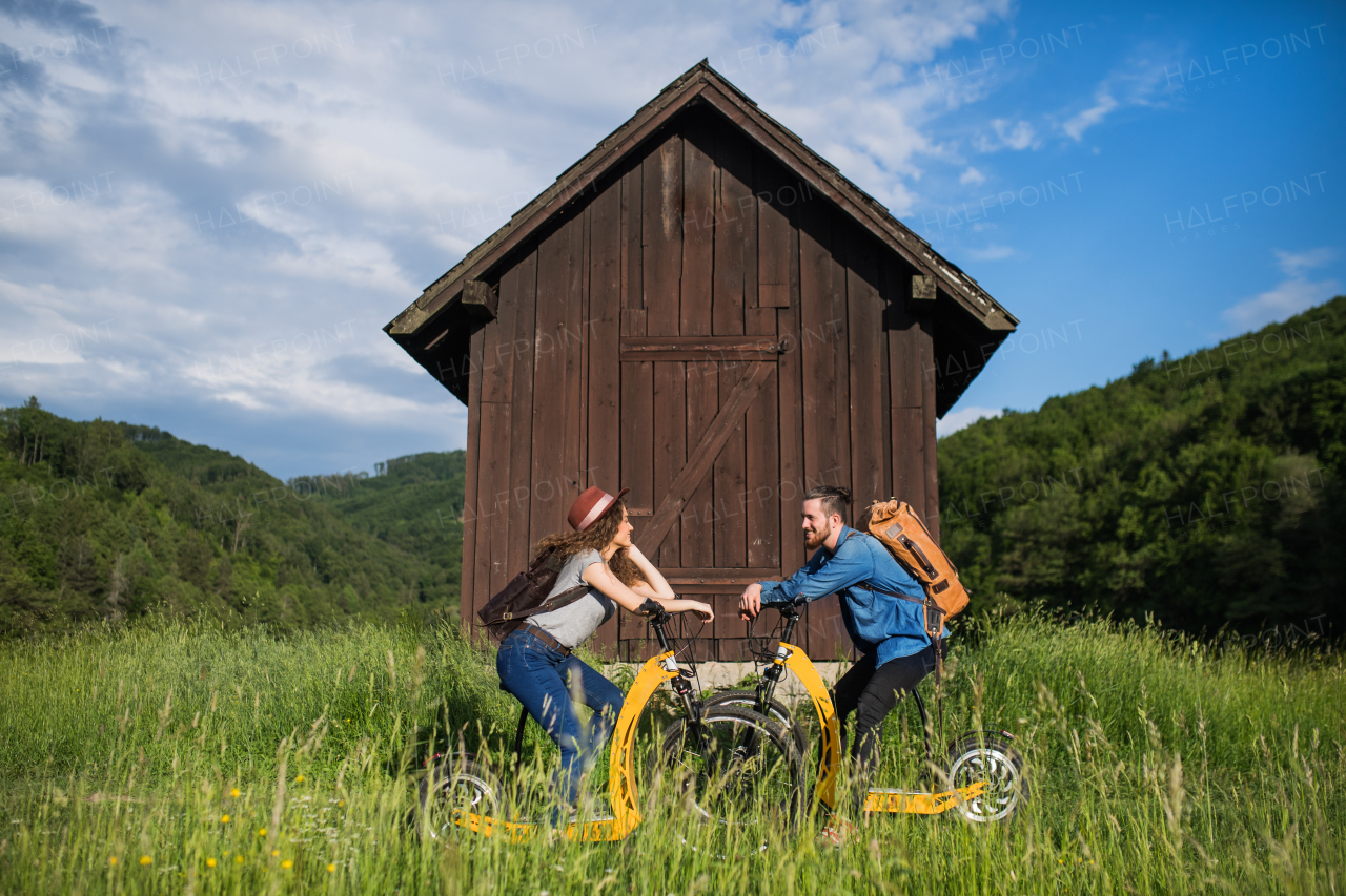 Young tourist couple travellers with backpacks and electric scooters in nature, resting.