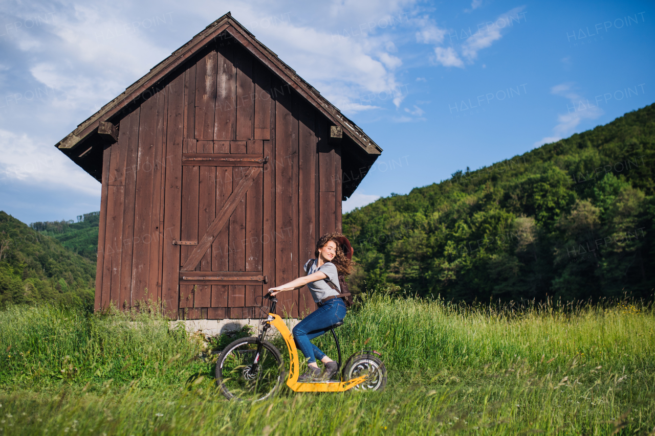 Young tourist woman traveller with electric scooter in nature, resting.