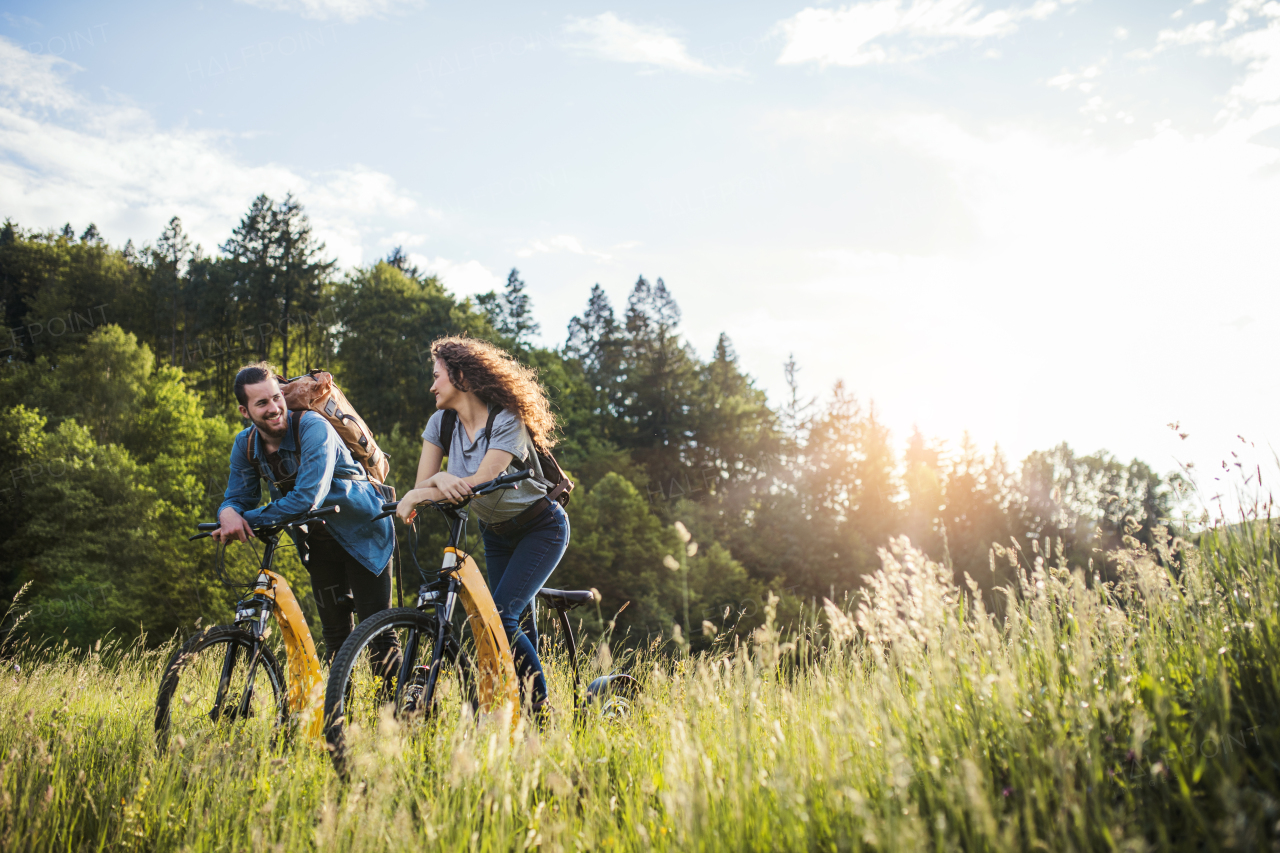 Young tourist couple travellers with backpacks and electric scooters in nature, resting.