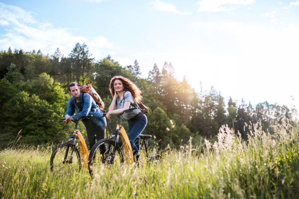 Young tourist couple travellers with backpacks and electric scooters in nature, resting. Copy space.