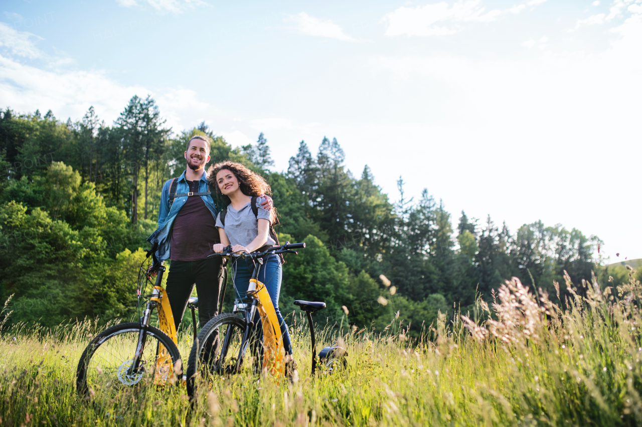 Young tourist couple travellers with backpacks and electric scooters in nature, resting.