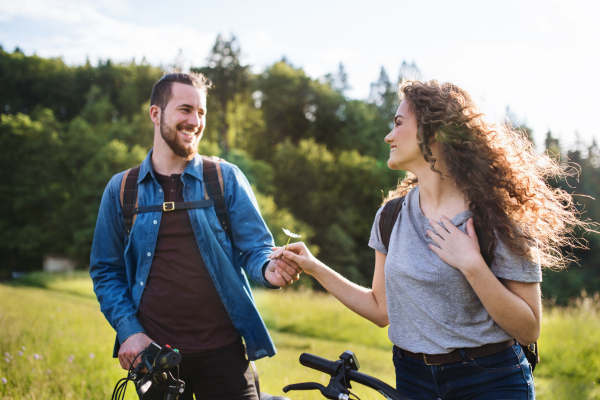 Young tourist couple travellers with backpacks and electric scooters in nature, resting.