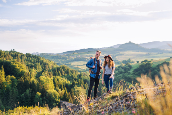 A young tourist couple travellers with backpacks hiking in nature, resting.