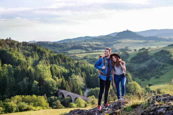 A young tourist couple travellers with backpacks hiking in nature, resting.