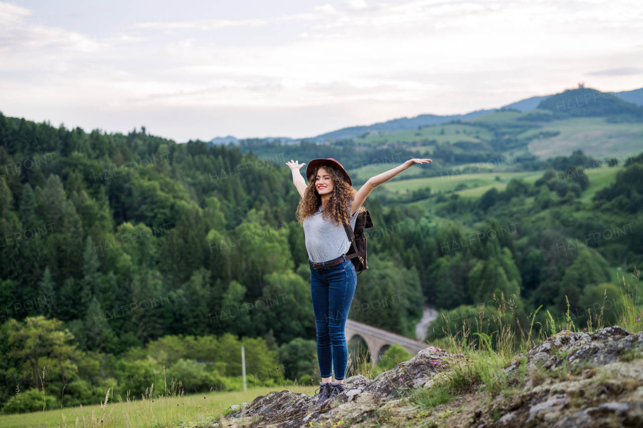 Happy young tourist woman hiker with backpack standing in nature, resting.