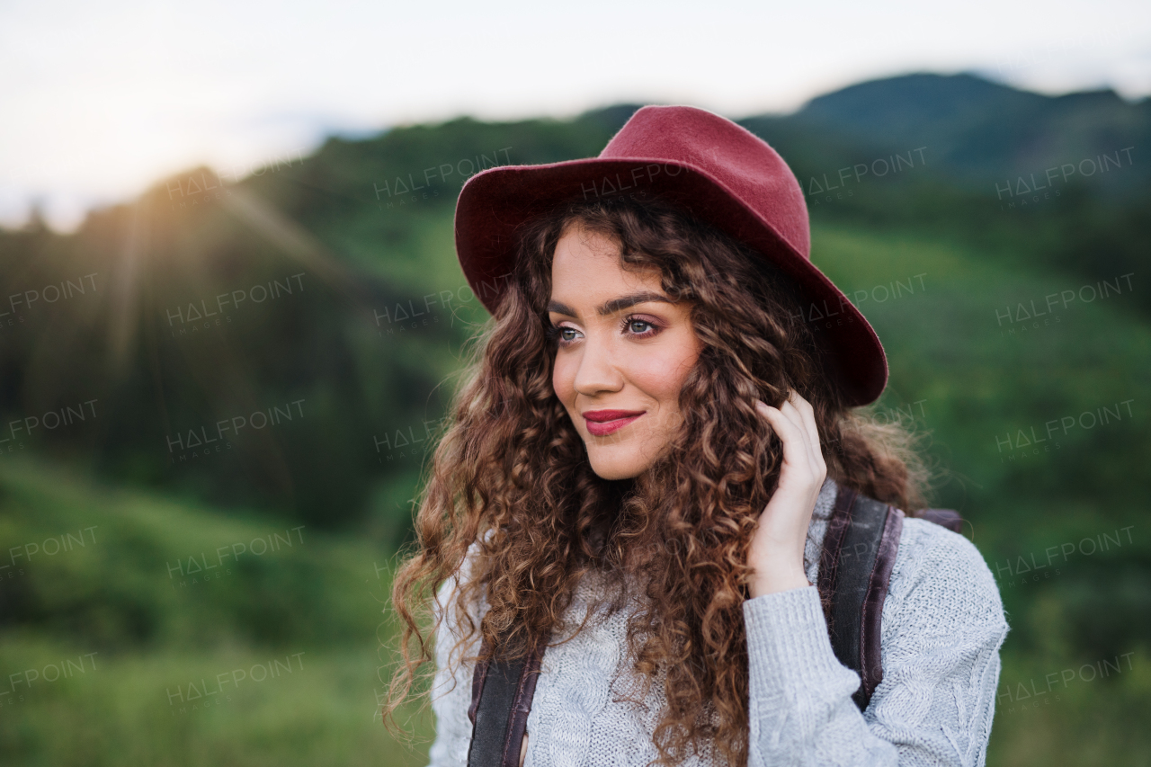 Young happy tourist woman traveller with backpack walking in nature at sunset.