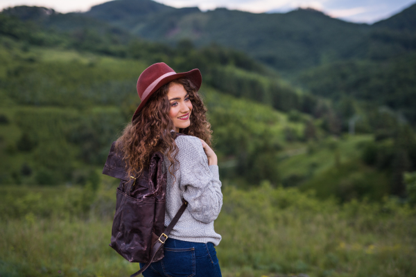 Young happy tourist woman traveller with backpack walking in nature.