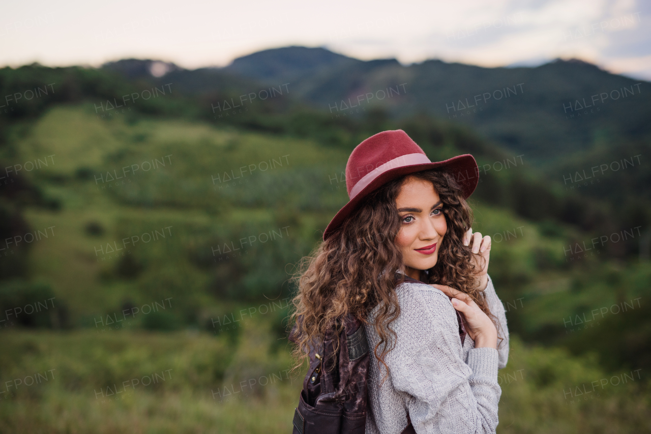 Rear view of young tourist woman traveller with backpack walking in nature, looking back.