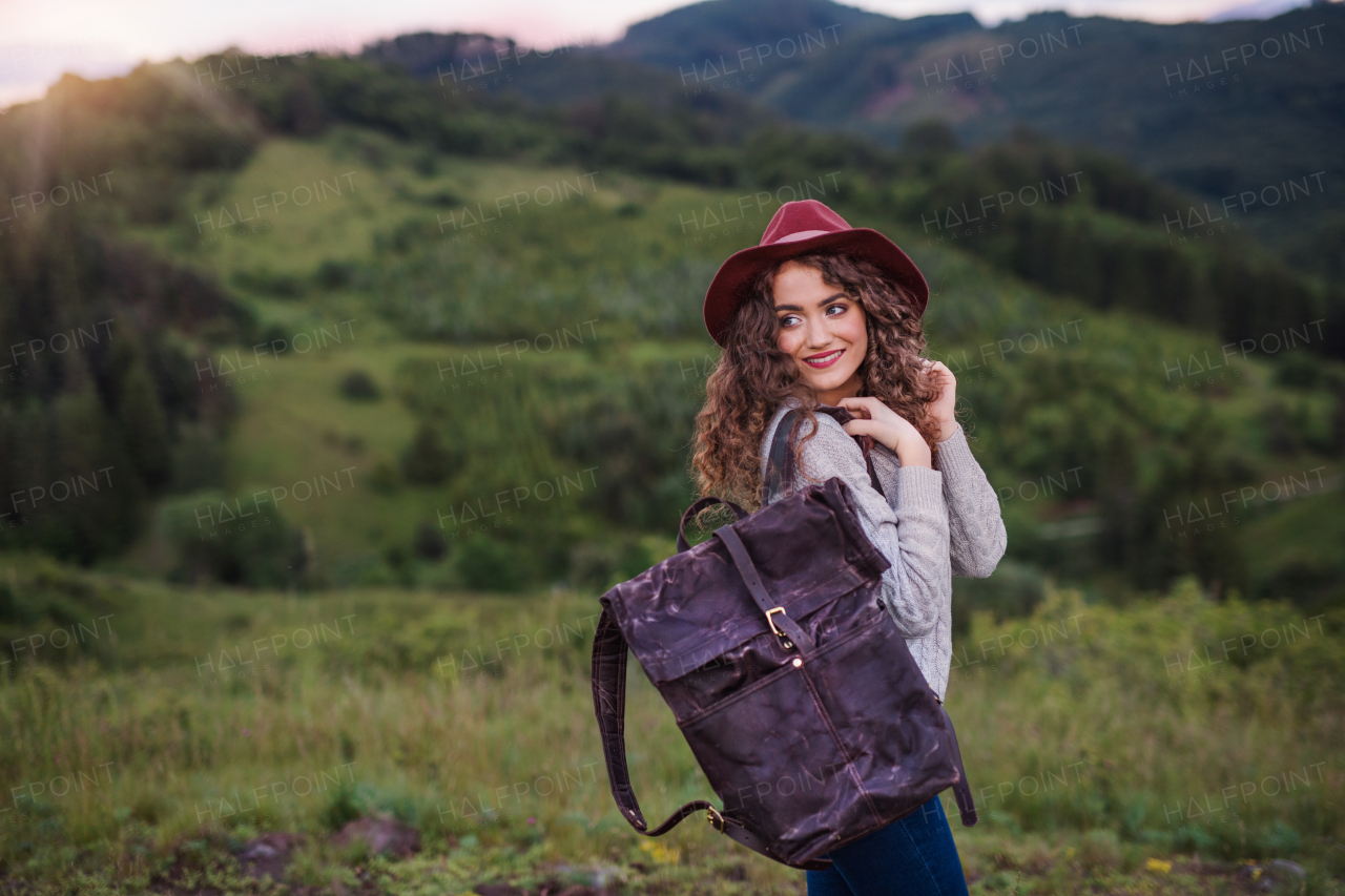 Rear view of young tourist woman traveller with backpack walking in nature, looking back.