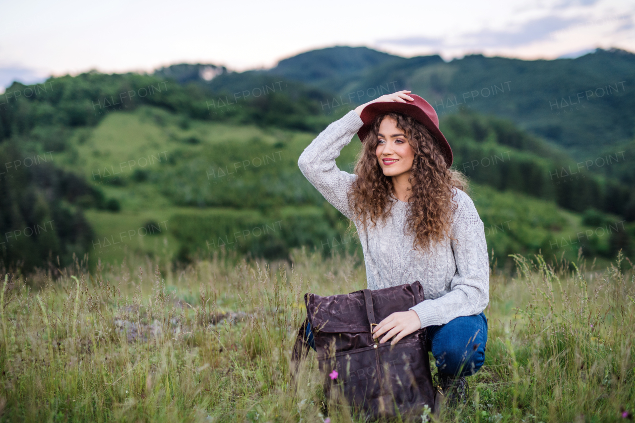 A young tourist woman traveller with backpack in nature, resting.