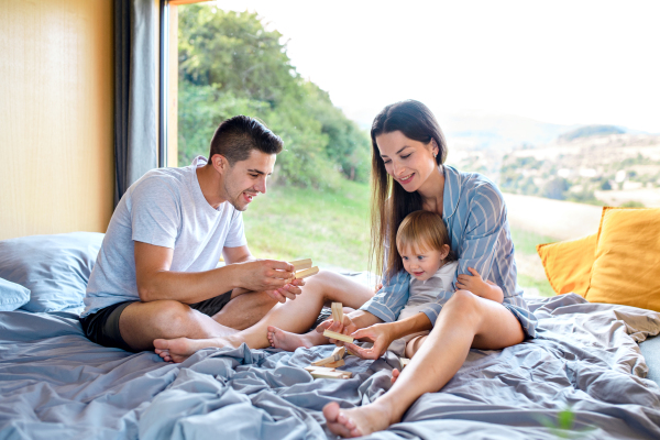 Young family with small daughter playing indoors, weekend away in container house in countryside.