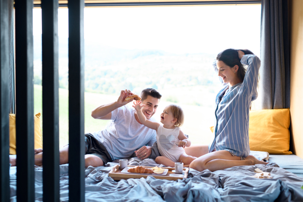 Young family with small daughter eating breakfast indoors, weekend away in container house in countryside.