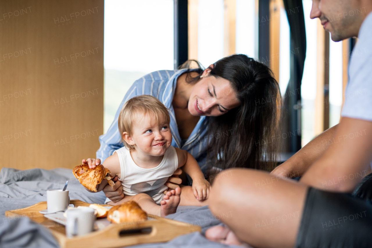 Young couple with small daughter eating breakfast indoors, weekend away in container house in countryside.