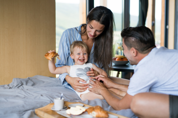 Young family with small daughter eating breakfast indoors, weekend away in container house in countryside.