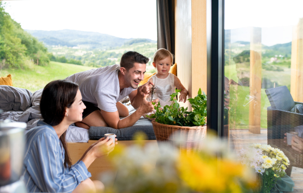 Happy young couple with small daughter indoors, weekend away in container house in countryside.