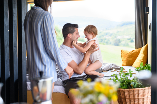 Young family with small daughter playing indoors, weekend away in container house in countryside.