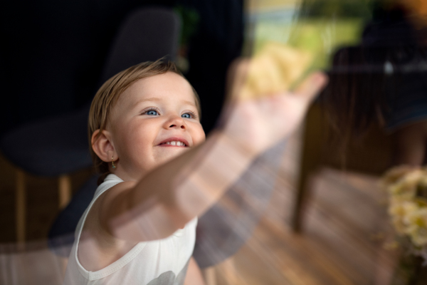 Small child playing indoors, weekend away in container house in countryside. Shot through glass.