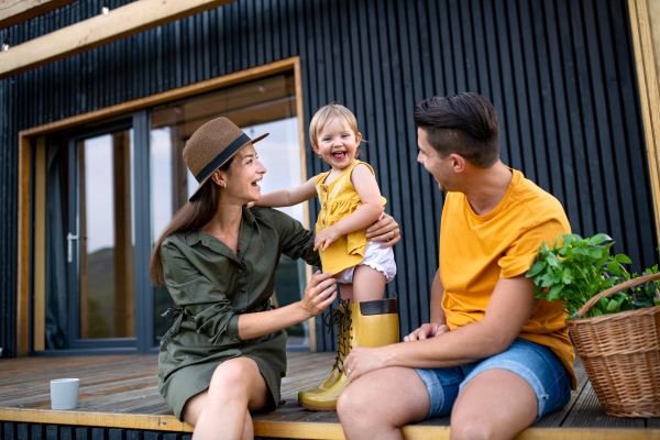 Young family with small daughter having fun outdoors, weekend away in container house in countryside.