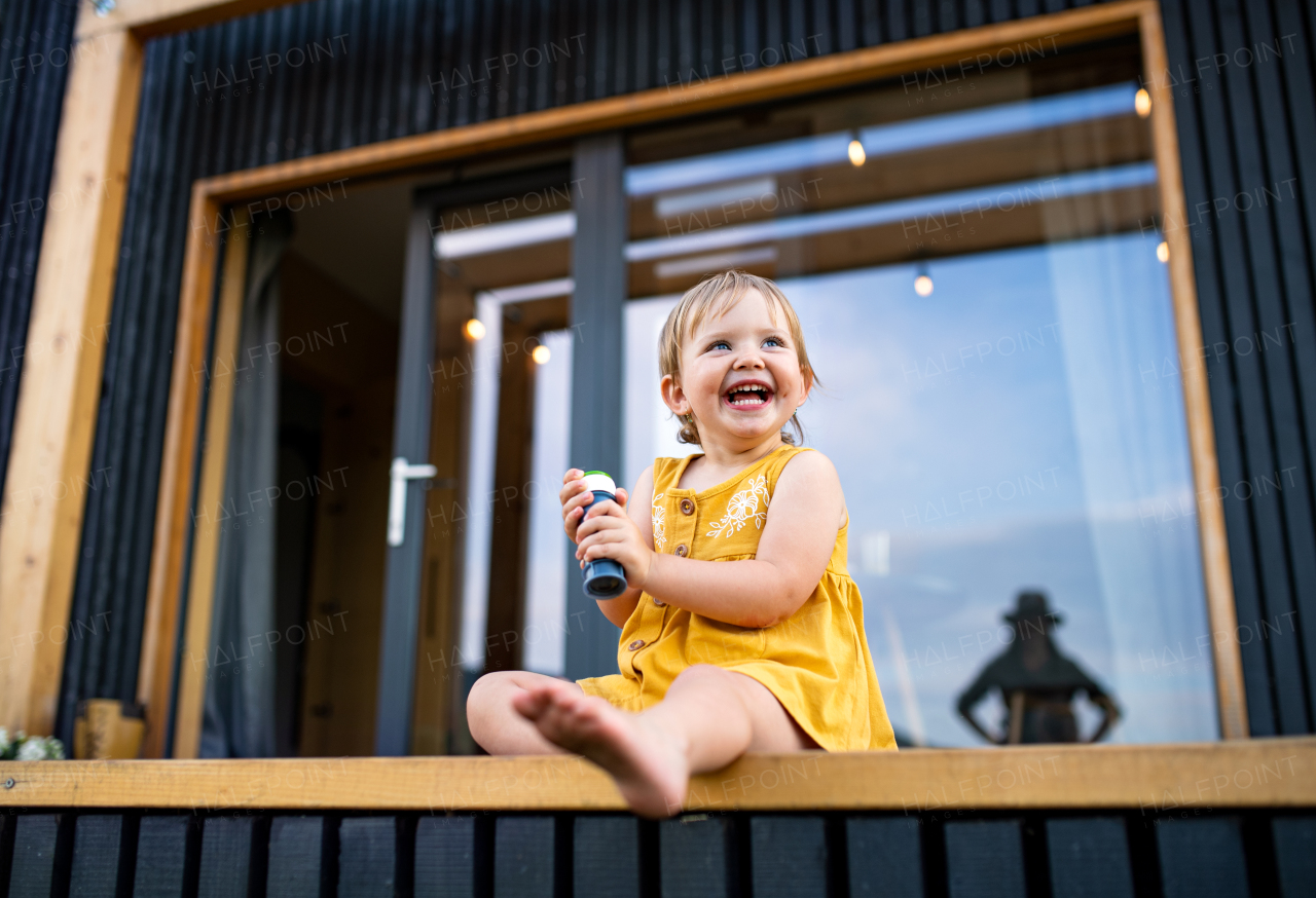 Happy small child playing outdoors, weekend away in container house in countryside.