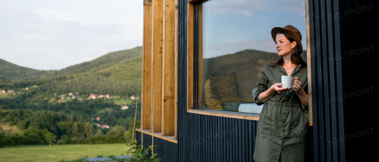 Young woman with coffee outdoors, weekend away in container house in countryside.