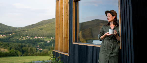 Young woman with coffee outdoors, weekend away in container house in countryside.