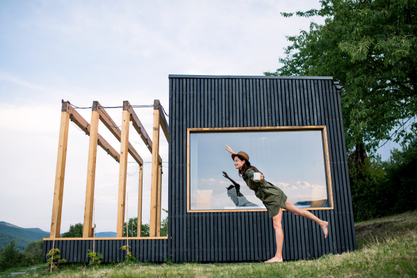 Young woman running outdoors, weekend away in container house in countryside.