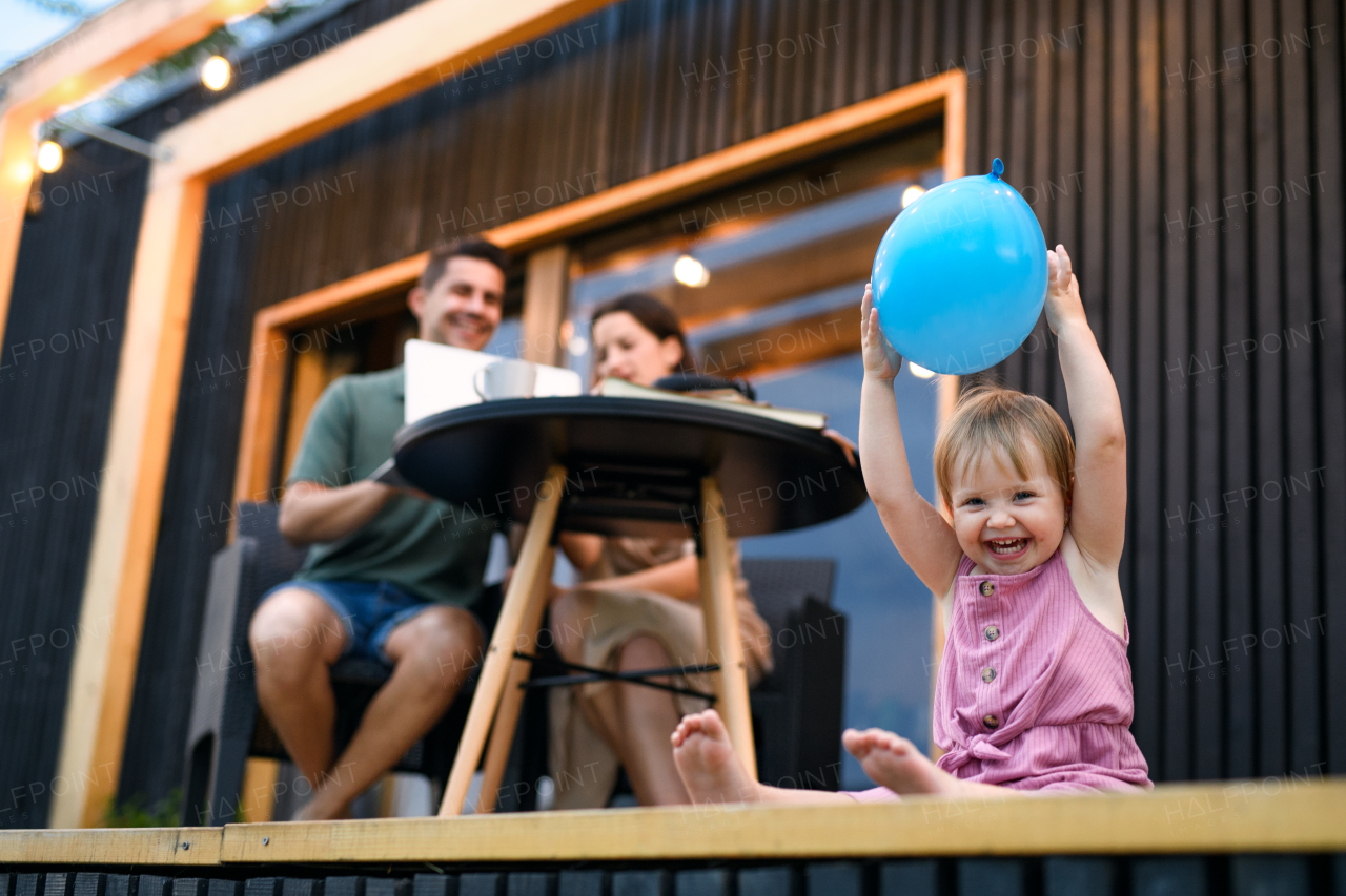 Young family with small daughter playing outdoors, weekend away in container house in countryside.