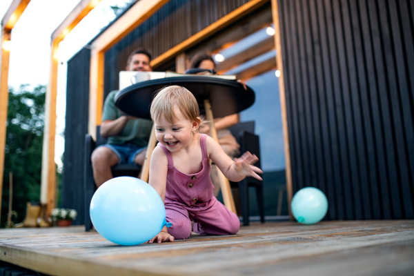 Young family with small daughter blowing bubbles outdoors, weekend away in container house in countryside.