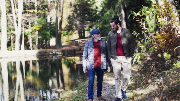 Senior father and his young son walking in nature, talking.