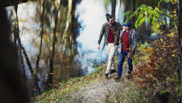 Senior father and his young son walking in nature, talking.