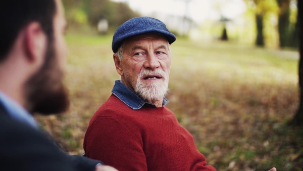 A senior father and his son sitting in nature, talking. Slow motion.