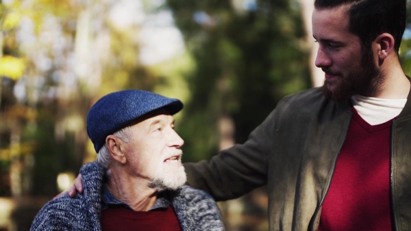 A senior father and his son sitting in nature, talking. Slow motion.