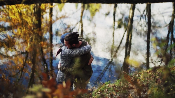 Top view of senior father and his son by lake in nature, hugging. Slow motion.